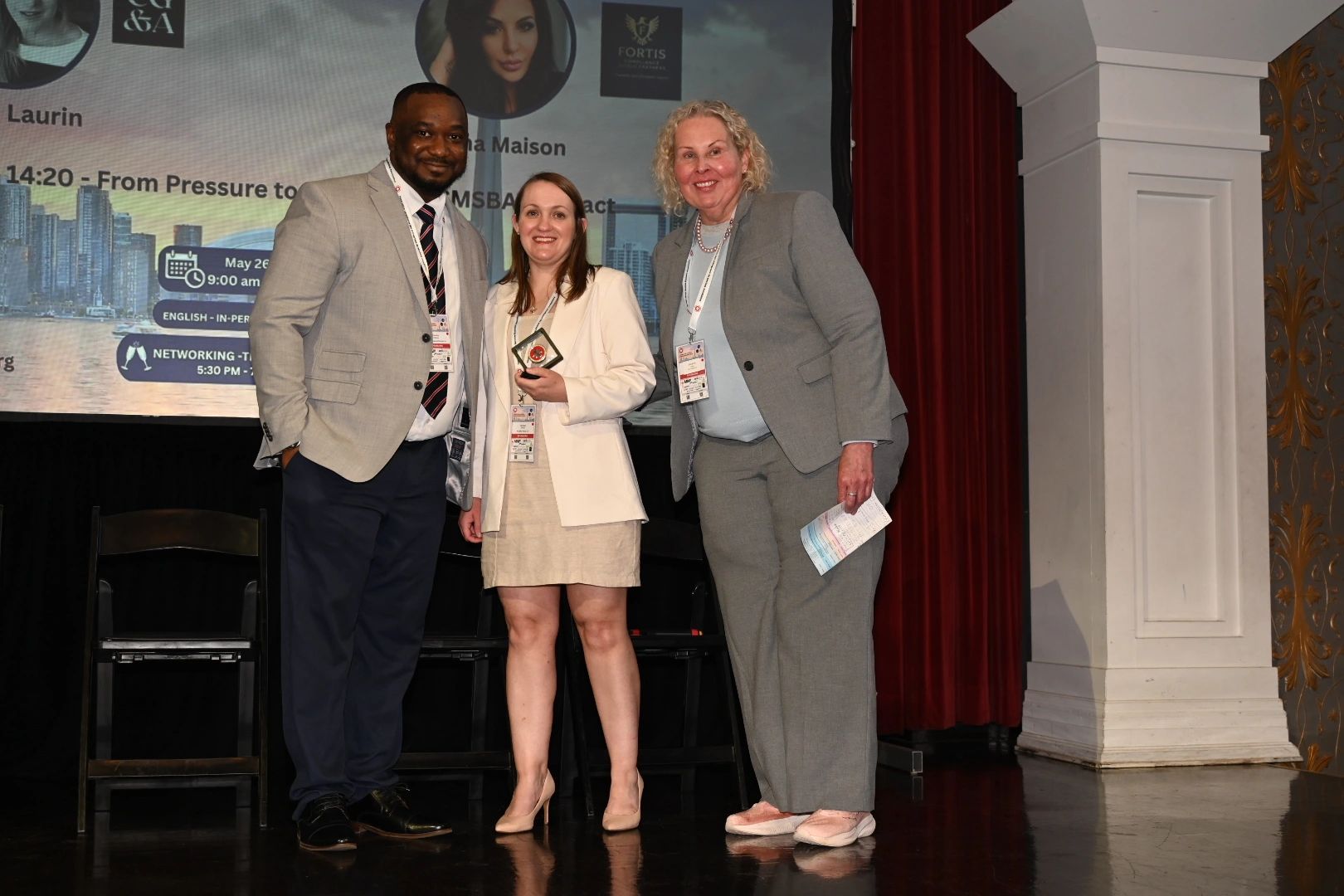 Claudius Otegbade with colleagues on stage at a compliance industry event